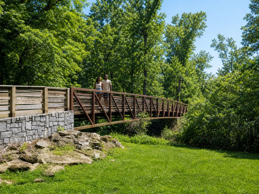 A couple walking across the steel trail footbridge in the Lionel Hampton-Beecher Hills Nature Preserve.